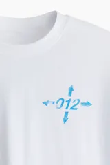 Remera deportiva blanca de corte boxy, confeccionada en tejido funcional DryMove™ que ayuda a absorber el sudor. Tiene cuello redondo ribeteado y hombros levemente caídos. Estampado en el frente con flechas y el número 012 en color celeste.