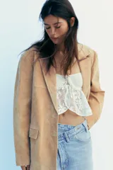 Blazer color camel confeccionada en piel de ante 100%. Diseño clásico con cuello solapa, escote pico, manga larga, bolsillos con solapa en delantero, forro interior combinado, bajo con abertura en espalda y cierre frontal con botones.