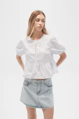 Blusa de algodón a rayas verticales color celeste y blanco, con cuello redondo, mangas cortas abullonadas y corte peplum.