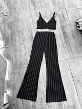 Conjunto de top corto con tirantes finos y pantalón oxford de tiro alto, ambos a rayas verticales blancas sobre fondo negro.