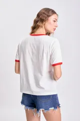 Remera blanca de manga corta con cuello y mangas con ribete rojo. Estampa frontal con diseño de cactus y texto en azul y rojo.