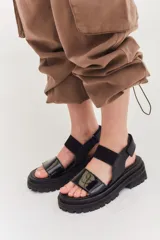 Sandalias de cuero color marrón con plataforma y suela track. Presentan dos tiras anchas, una de cuero liso y otra con textura tipo piel de reptil.