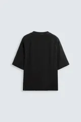 Camiseta negra de corte holgado, cuello redondo y mangas cortas. Tiene un efecto de lavado que le da una apariencia única.