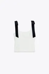 Top blanco de tejido elástico con escote cuadrado y tirantes con lazos decorativos. Tiene forro interior y cierre lateral con cremallera oculta.
