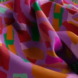 Pañuelo cuadrado de seda con estampado caleidoscópico multicolor en tonos orquídea, naranja, verde y rojo. Edición limitada de 10 unidades.
