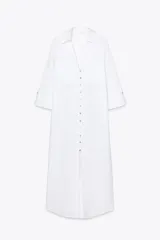 Vestido camisero blanco de lino, con cuello solapa, escote en pico, manga tres cuartos con trabilla y botón, bolsillos delanteros de parche, aberturas laterales en el bajo y cierre frontal con botones.