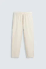 Pantalón color crudo de corte recto, confeccionado en tejido de algodón con textura. Cuenta con cintura elástica ajustable con cordón, bolsillos laterales y traseros de vivo.