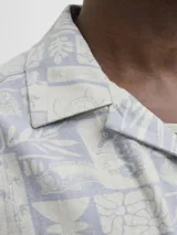 Camisa de manga corta Jack & Jones con cuello resort y calce amplio. Presenta un estampado integral de motivos náuticos y abstractos en tonos azul chambray y beige. Confeccionada en una mezcla de viscosa y lino, ideal para climas cálidos.