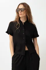 Camisa negra de lino con cuello mao y volados en cuello y mangas cortas.