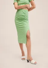 Falda midi de tiro alto con estampado a cuadros vichy en verde y blanco, con frunce lateral y abertura en el ruedo.