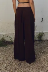 Pantalón marrón de tiro alto con cintura elástica en la espalda, bolsillos laterales, pliegues en la parte delantera y bordados combinados a tono en el ruedo.