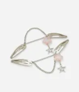 Set de cuatro pinzas para el pelo plateadas, unidas por cadenas y adornadas con cuentas rosadas en forma de estrella y dijes colgantes de estrellas.