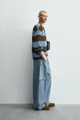 Pantalón de jean celeste de corte holgado y amplio en toda la pierna, tiro medio, tejido rígido, cinco bolsillos, efecto lavado, parche en trasero y bolsillo de vivo en pernera.