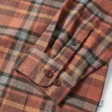 Camisa de franela a cuadros color ladrillo, con dos bolsillos frontales con solapa abotonada y mangas largas.