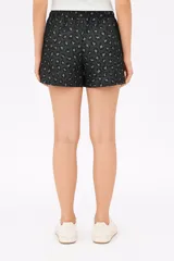 Short negro con estampado de flores blancas, de poliéster, holgado y de calce medio.