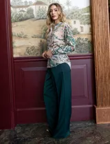 Pantalón palazzo de tiro alto color violeta, de satén. Tiene pretina delantera con pasadores, botón y cierre, pretina trasera elastizada y bolsillos verticales delanteros.