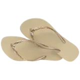 Sandalias Havaianas Slim Glitter II color beige con tiras finas con glitter dorado.