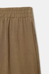 Pantalón marrón de tiro alto con cintura elástica, bolsillos delanteros y pernera ancha.