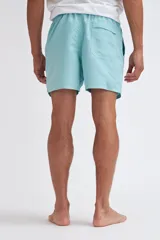 Short de baño azul marino con estampado de hojas blancas y rojas.