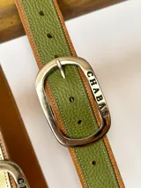 Cinto de cuero con punta en colores variados y hebilla metálica rectangular.