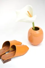 Zuecos color naranja con capellada tejida, taco bajo de madera y suela antideslizante.