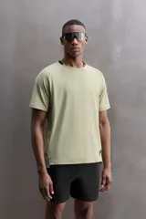 Camiseta deportiva verde militar confeccionada en tejido estructurado, ligero y elástico. Tiene cuello redondo, manga corta y bajo con aberturas laterales. Incluye logo estampado en el bajo.
