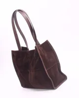 Bolso tipo shopper de cuero color marrón chocolate, con doble asa de hombro y cierre de botón magnético. Incluye un bolsillo interior con cierre de cremallera.
