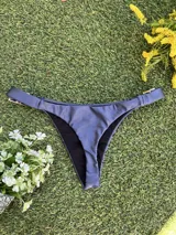 Conjunto de bikini azul con corpiño de breteles finos y hebillas metálicas en los tirantes. La bombacha es colaless y también tiene hebillas metálicas en los laterales.