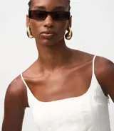 Top blanco de algodón con escote cuadrado, breteles finos y peplum ajustado a la cintura.