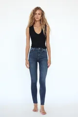 Jeans skinny de tiro alto en denim azul oscuro, con cinco bolsillos y cierre frontal con cremallera y botón metálico.