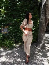 Vestido de dos piezas color beige, compuesto por un top corto con mangas cortas y una falda midi con volados. Incluye cinturón de cuero marrón.