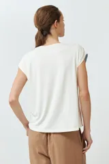 Blusa sin mangas con estampado floral en tonos celeste y naranja sobre fondo blanco. Presenta cuello redondo y corte recto.