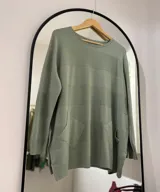 Sweater verde oliva de tejido de punto con cuello redondo, manga larga, bolsillos delanteros y puños y bajo acanalados.