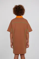 Vestido tipo polo oversize de algodón color rosa, con cuello en contraste azul y detalles de bies.