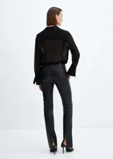 Pantalón entallado de efecto piel negro, con tiro medio y costuras decorativas.