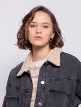 Campera de jean color azul con forro de corderito, bolsillos frontales y laterales, elástico en la cintura y detalles en las mangas.
