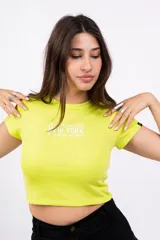 Remera corta color verde lima, de corte ajustado y mangas cortas. Presenta estampado frontal con la leyenda "Manhattan 1990 New York".