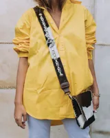 Camisa de manga larga color amarillo con cuello y botones frontales. Presenta un bordado dorado con el texto "Sierra Mora" en el cuello.