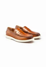 Mocasines color marrón de cuero con antifaz y suela de goma blanca.