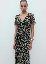 Vestido midi negro con estampado de pequeñas flores blancas, escote en V, mangas cortas con volantes y corte ajustado en la cintura.