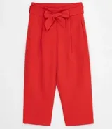 Pantalón pantacourt rojo con pinzas en la cintura, bolsillos laterales y lazo en la cintura.