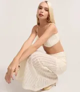 Pollera de largo new midi confeccionada en tejido de punto con aplicación de lentejuelas en toda la prenda. Presenta un diseño ajustado al cuerpo, forro interno y cintura elástica.