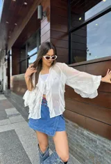 Blusa blanca traslúcida con mangas largas acampanadas con volados. Escote en V.