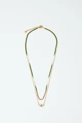 Set de dos collares dorados. Uno es una cadena con cuentas verdes y blancas. El otro es una cadena con un dije de ojo turco con incrustaciones de strass azul.