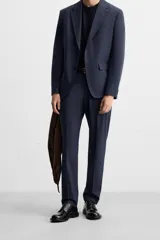 Pantalón de vestir azul marino, de corte slim fit, con bolsillos laterales y traseros de doble vivo con botón. Se ajusta a la cintura con cierre frontal con cremallera y botón.