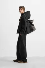 Sudadera con capucha negra, de corte oversize, confeccionada en tejido de algodón con interior en rizo. Cuenta con manga larga, bolsillos frontales tipo canguro, efecto lavado y acabados irregulares con vuelta.
