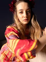 Top corto color crema con estampado de cachemir en tonos naranja y rosa, escote elástico con volantes, mangas cortas abullonadas y corte crop.