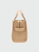 Bolso tote pequeño de cuero texturizado color gris con doble asa corta superior y correa larga extraíble y ajustable para llevar al hombro. Estampado frontal con el texto "The Tote Bag" y el nombre de la marca.