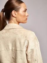 Campera boxy color beige con cuello solapa, manga larga, bolsillos delanteros y cierre frontal con botones a presión.