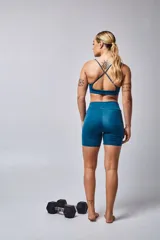 Top deportivo color beige con banda inferior azul y tirantes finos azul marino. Espalda cruzada con doble tira.